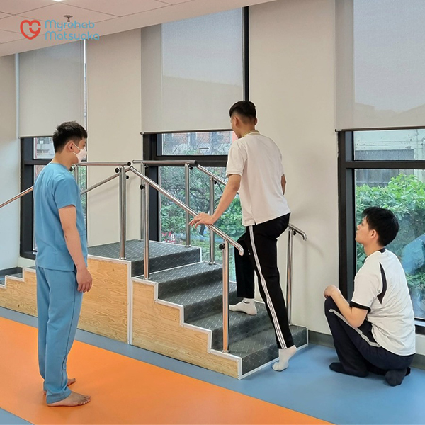 Bệnh nhân tập lên xuống cầu thang dưới sự hướng dẫn và quan sát của kỹ thuật viên tại Myrehab Matsuoka